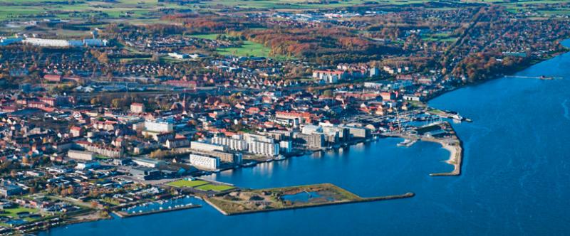 Skråt flyfoto viser marinalandskab foran by