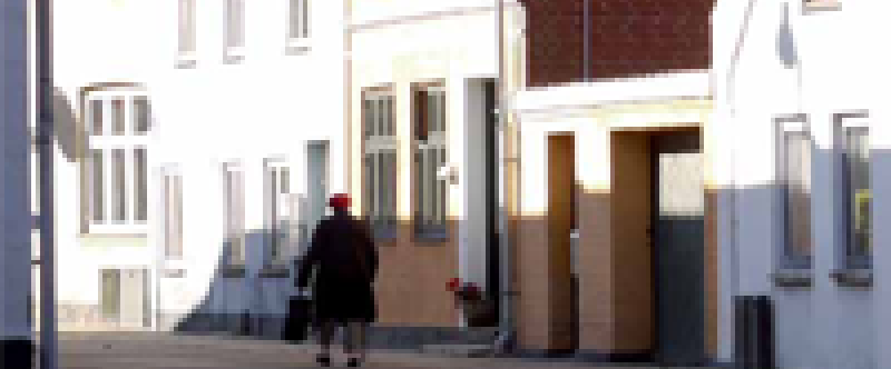 Ældre dame spadserende foran bygninger